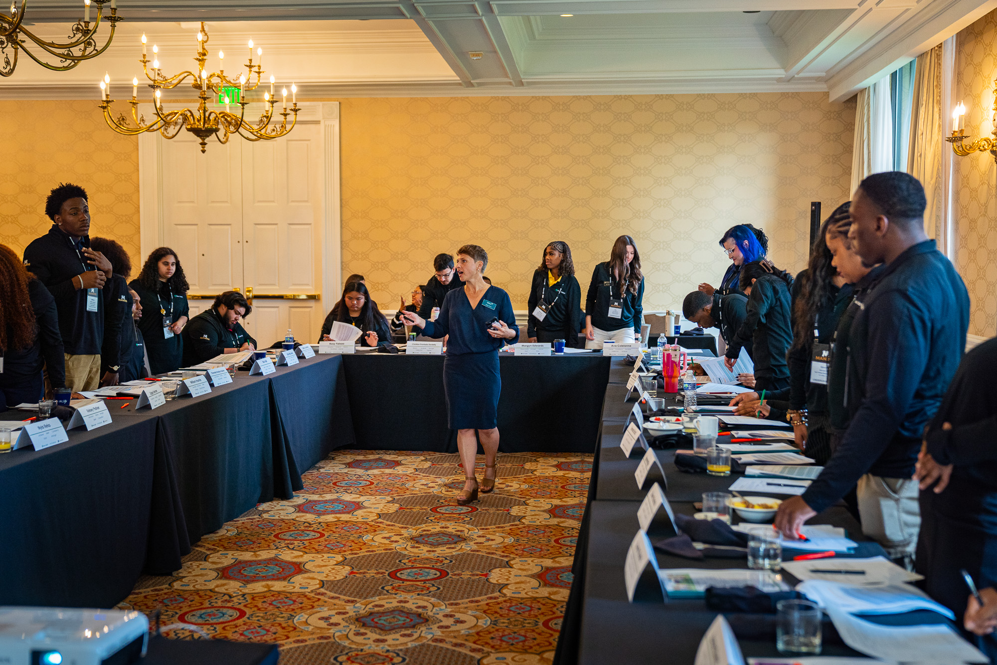 A seminar room in session, attendees seated around U-shaped tables