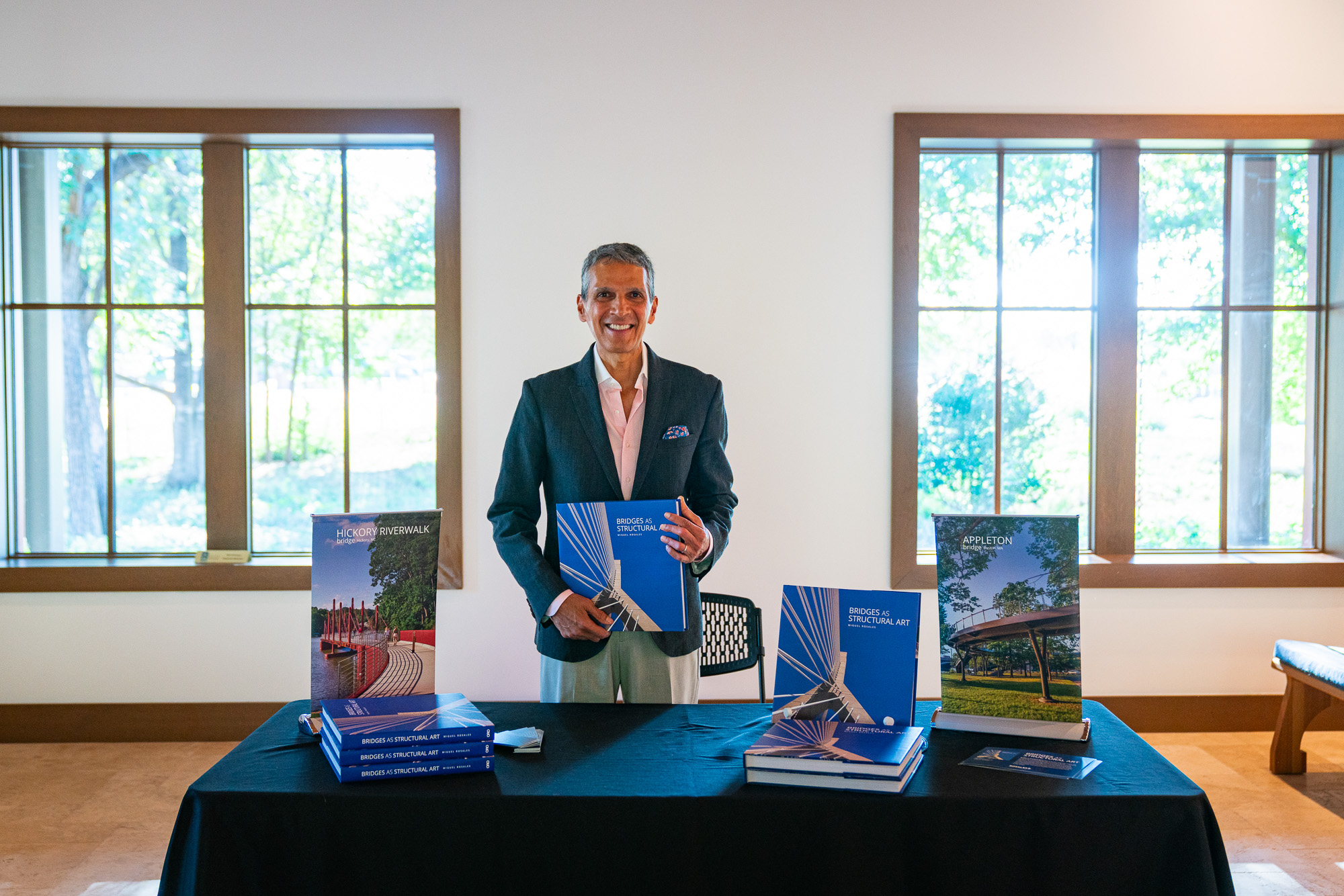 The author standing behind his book table, holding a copy
